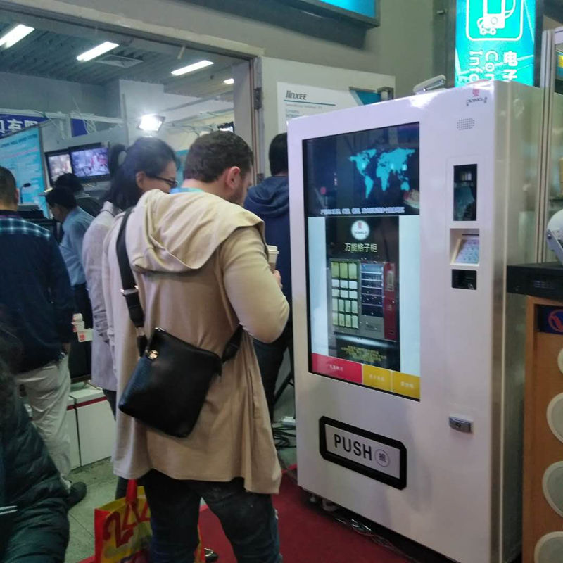 Customers interacting with touchscreen vending machine at exhibition