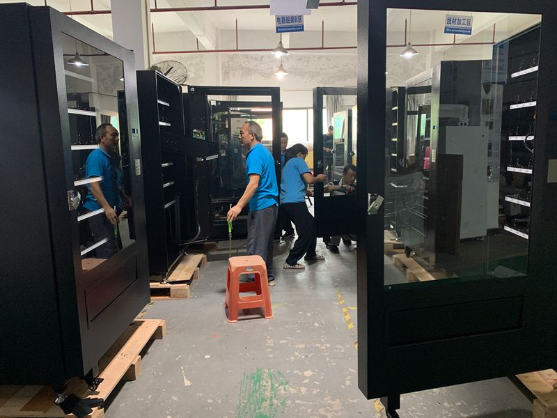 Workers assembling vending machines in factory